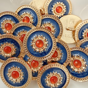 May include: A collection of round buttons featuring a deep blue enamel center, a gold-toned scalloped sunflower-shaped border, and a central orange cabochon. Each button has a gold-toned metal back with a shank for attachment and a textured finish.