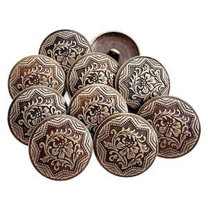 May include: A collection of antique bronze-colored buttons with intricate floral and geometric patterns. The buttons are round with a slightly domed shape, and the detailed designs are raised against a darker background. The buttons are arranged on a white background.