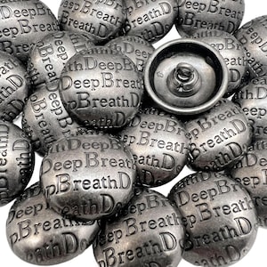 May include: A collection of silver-toned metal buttons with the words "Deep Breath" embossed on each. The buttons have a slightly weathered appearance, and one button is shown from the back, revealing the clasp.