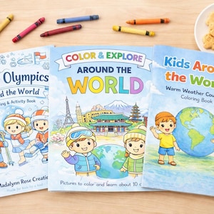 Puede incluir: Tres libros para colorear para niños con los títulos "Winter Olympics Around the World", "Color & Explore Around the World" y "Kids Around the World". Creyones de varios colores y un plato pequeño con galletas con forma de oso están dispersos alrededor de los libros.