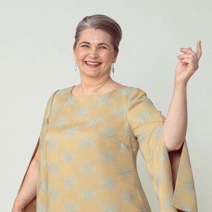 May include: A light yellow knee-length dress with a floral pattern and split sleeves. The dress is worn with brown heels. The image is a full-body shot of a person.