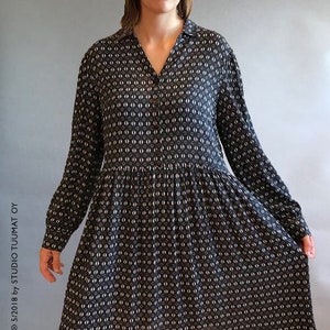 May include: A black dress with a white geometric pattern. The dress has long sleeves, a collared neckline, and a V-neck. It features a gathered waist and a flared skirt. The dress falls to the knees.