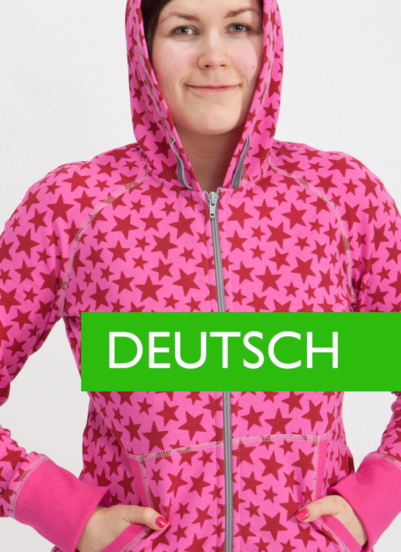 Puede incluir: Una sudadera con capucha rosa con un estampado de estrellas rojas. La sudadera tiene una cremallera gris y una capucha con cord&oacute;n. El texto "DEUTSCH" est&aacute; impreso en una pancarta verde en la parte delantera de la sudadera.