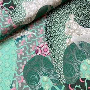 May include: A green and white fabric with a geometric pattern. The fabric features a variety of shapes and designs, including circles, squares, and triangles. The fabric is made of a soft, comfortable material and is perfect for a variety of projects.