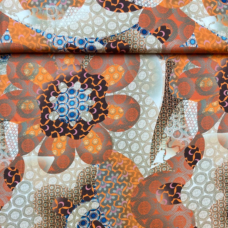May include: A fabric with a repeating pattern of orange, brown, and blue flowers. The flowers are made up of smaller circles and swirls. The background is white with a subtle pattern of small circles.
