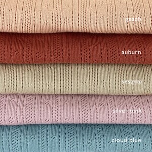 Peut inclure: Cinq &eacute;chantillons de tissu en tricot de diff&eacute;rentes couleurs empil&eacute;s les uns sur les autres. Les couleurs sont p&ecirc;che, auburn, s&eacute;same, rose argent&eacute; et bleu nuage.