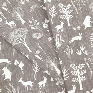 May include: Gray fabric with a white woodland pattern. The pattern includes trees, deer, rabbits, mushrooms, and other foliage.