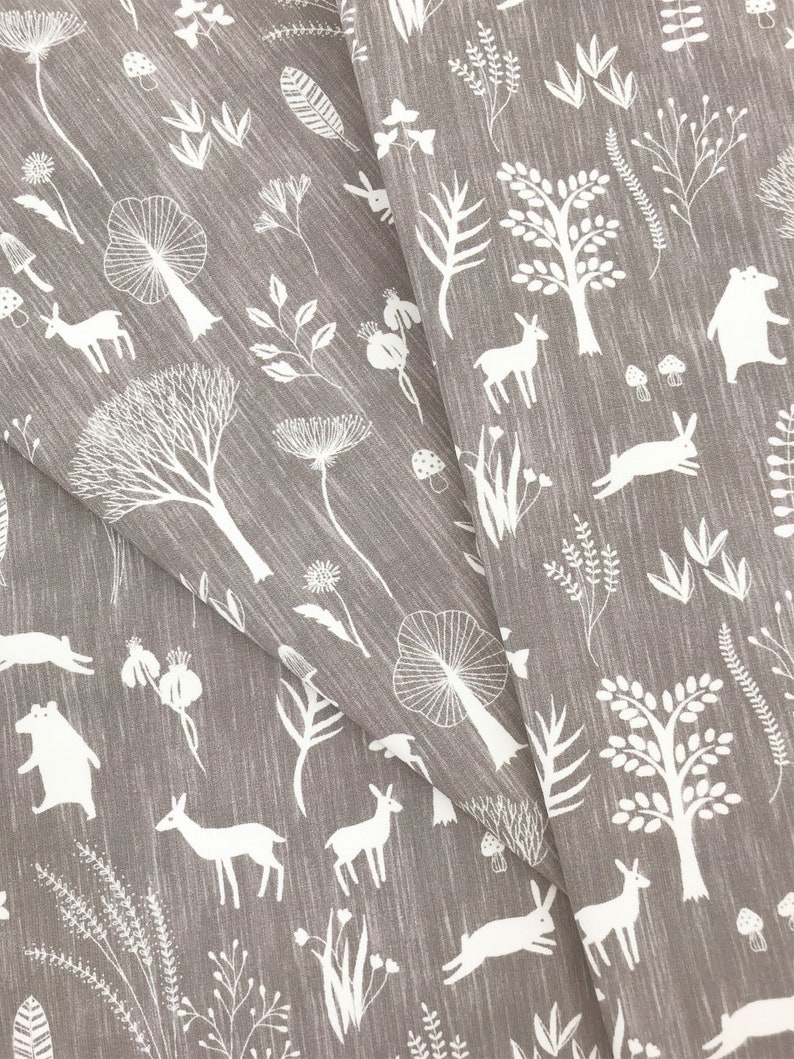 May include: Gray fabric with a white woodland pattern. The pattern includes trees, deer, rabbits, mushrooms, and other foliage.