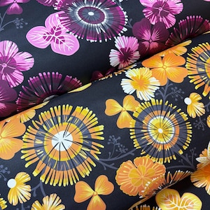 May include: Close-up of two rolls of fabric with a floral pattern. One roll features purple and pink flowers, while the other displays orange and yellow flowers. Both rolls have a dark background, creating a striking contrast with the colorful floral designs.