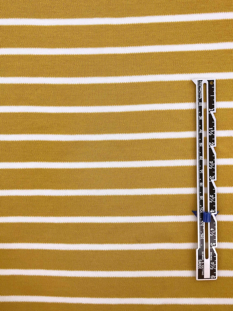 May include: Mustard yellow and white striped fabric with a ruler measuring 6 inches.
