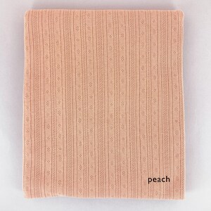 Peut inclure: Tissu de couleur p&ecirc;che avec un motif textur&eacute; et c&ocirc;tel&eacute;. Le tissu a un l&eacute;ger brillant et une sensation douce et fluide.