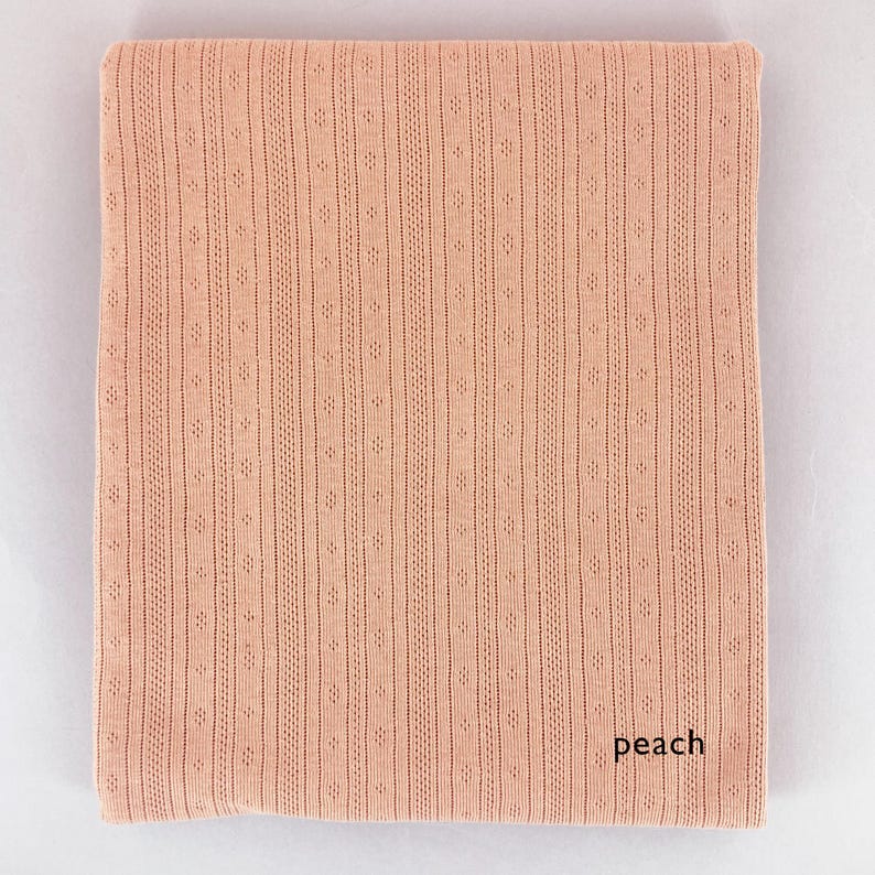 Peut inclure: Tissu de couleur p&ecirc;che avec un motif textur&eacute; et c&ocirc;tel&eacute;. Le tissu a un l&eacute;ger brillant et une sensation douce et fluide.