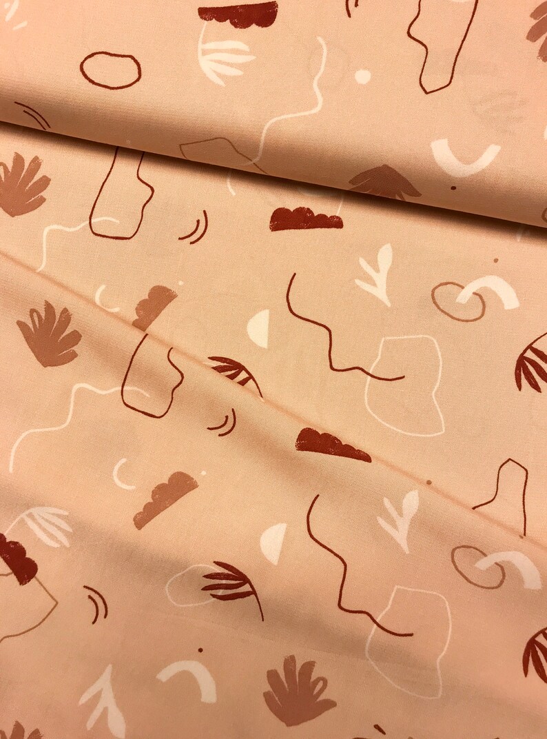 May include: A beige fabric with a repeating pattern of abstract shapes and lines in shades of brown and white.