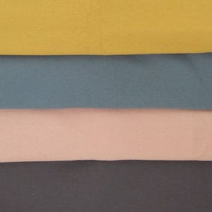 Puede incluir: Cuatro muestras de tela en diferentes colores: amarillo mostaza, azul turquesa, rosa claro y gris oscuro.