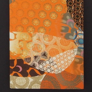 May include: A collage of orange, brown, white, and blue patterned fabric scraps. The fabric has a variety of geometric and floral designs.