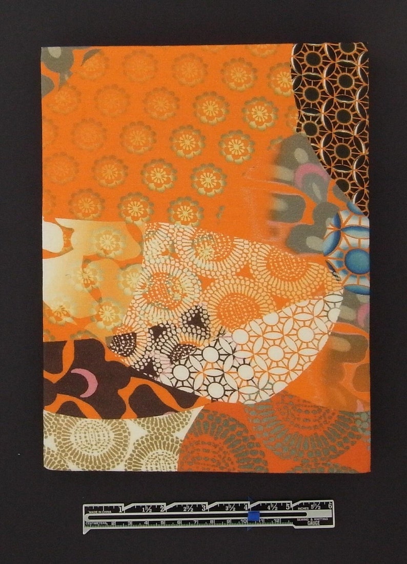 May include: A collage of orange, brown, white, and blue patterned fabric scraps. The fabric has a variety of geometric and floral designs.