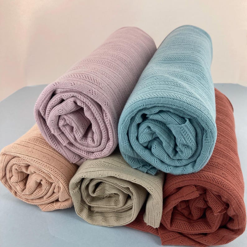 Peut inclure: Quatre rouleaux de tissu de diff&eacute;rentes couleurs&nbsp;: rose p&acirc;le, bleu clair, beige et rouille. Le tissu a une texture &agrave; armure ouverte.