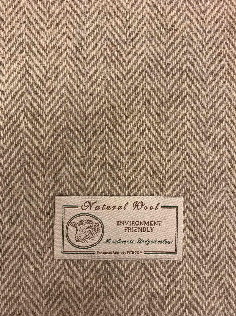 Puede incluir: Un primer plano de una tela de espiga marr&oacute;n y blanca con una etiqueta que dice "Natural Wool - Environment Friendly - No colorants - Undyed colour - European Fabrics by FITECOM".