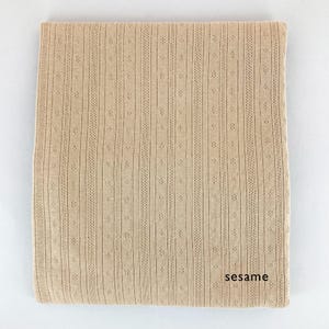 Peut inclure: Un tissu tricot&eacute; beige avec un motif textur&eacute;. Le tissu a un l&eacute;ger brillant et une sensation douce et fluide. Le tissu est &eacute;tiquet&eacute; "sesame".