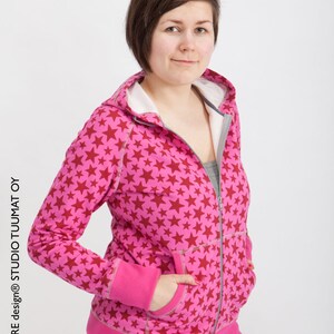 Puede incluir: Una sudadera con capucha rosa con un estampado de estrellas rojas. La sudadera tiene una cremallera y dos bolsillos.