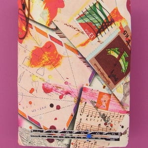 May include: A pink and white fabric with a collage of colorful images, including stamps, musical notes, and handwritten notes. The fabric features a ruler with markings in inches.