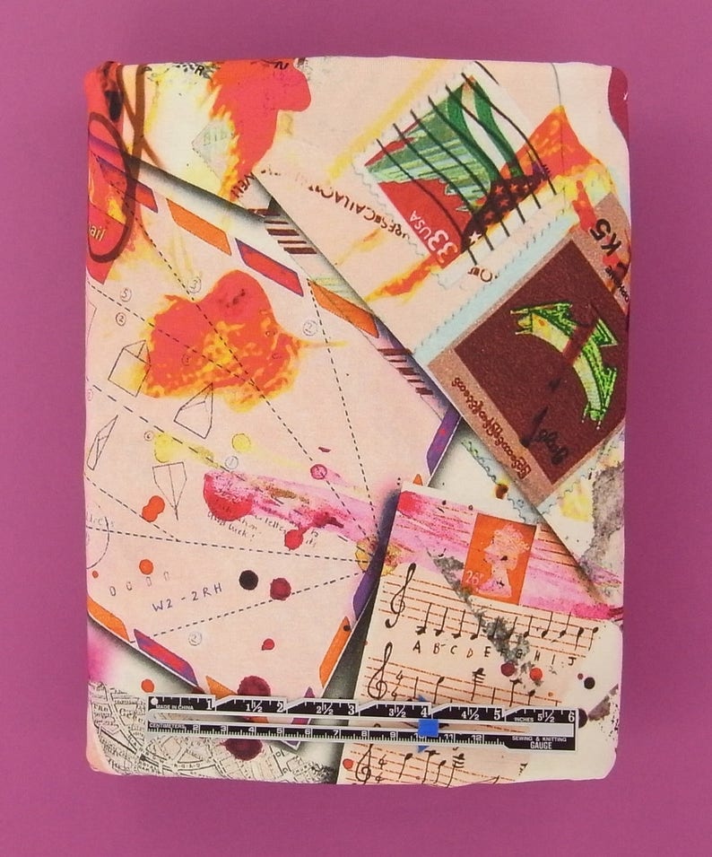 May include: A pink and white fabric with a collage of colorful images, including stamps, musical notes, and handwritten notes. The fabric features a ruler with markings in inches.