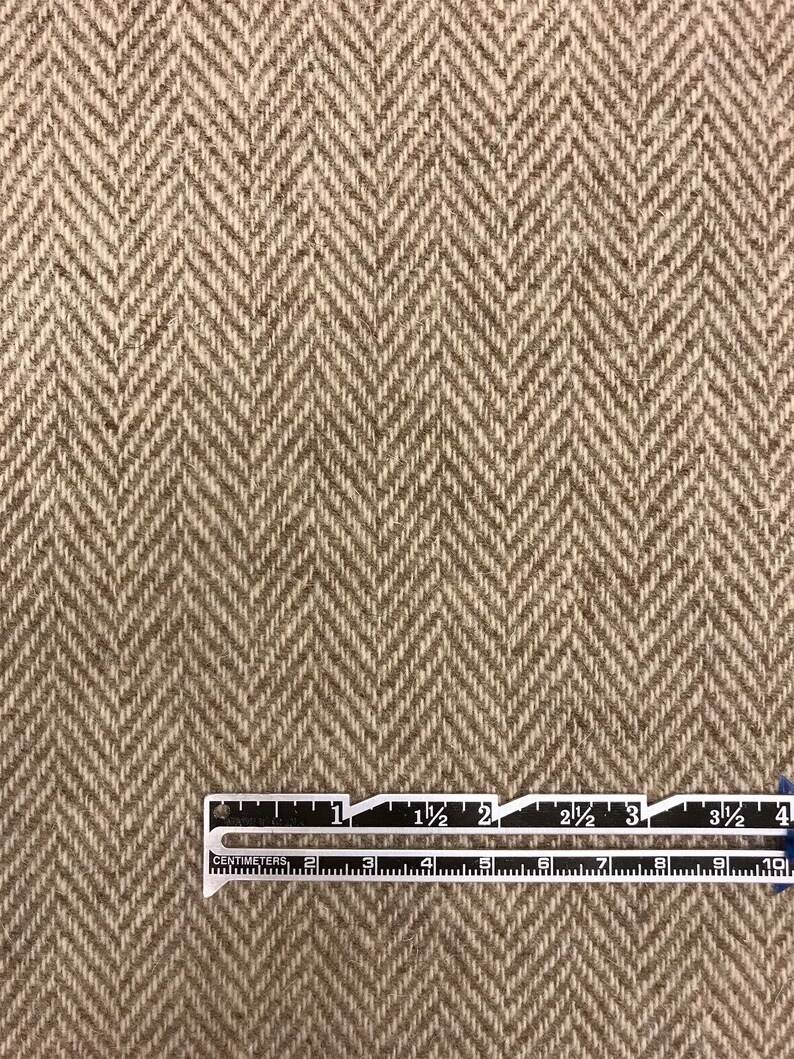 Puede incluir: Primer plano de una tela de espiga marr&oacute;n y beige con una regla que mide 10 cm.