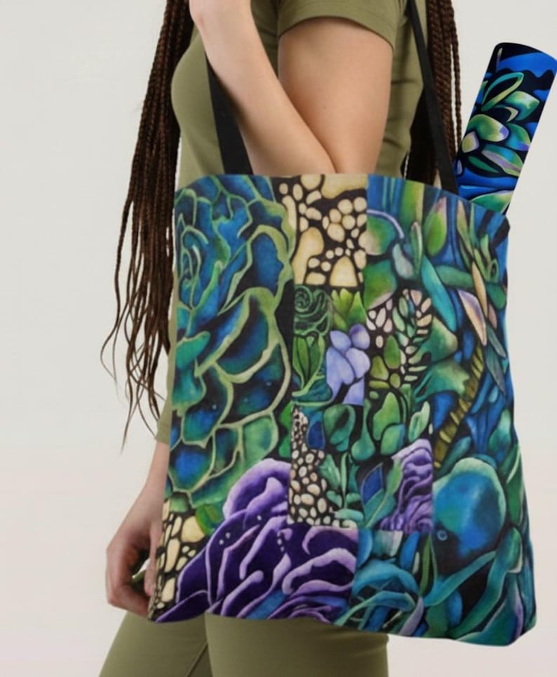 May include: A tote bag with a vibrant botanical design featuring blue, green, and purple succulents. The bag has black straps and a matching rolled-up item inside. The artwork is detailed and colorful, creating a striking visual appeal.