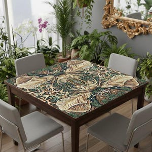 May include: A square wooden table with a botanical print tabletop featuring large, stylized leaves in shades of beige, green, and brown. Four gray chairs surround the table, set in a room with plants and a decorative mirror.