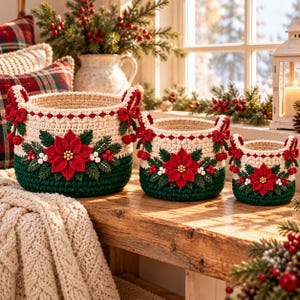 May include: A set of three round, crocheted baskets in descending sizes, featuring a cream-colored upper section and a dark green base. Each basket is decorated with a red poinsettia, green leaves, white berries, and small red bows.
