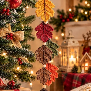 Peut inclure: Une décoration suspendue verticale composée d'une série de feuilles de chêne crochetées en jaune, rouge, vert et marron, séparées par de petites perles en bois, se terminant par un gland crocheté, suspendue par une boucle en ficelle de jute.