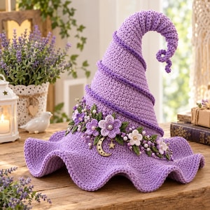 May include: A lavender crochet witch hat featuring a spiraling design, adorned with a band of crocheted purple and white flowers, green leaves, small white pearls, and a gold-toned crescent moon and star charm attached to the front brim.