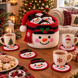 Könnte beinhalten: Ein weißer, gehäkelter Schneemann-Korb mit roter Mütze und Schal, gefüllt mit kleinen Schneemann-Ornamenten. Das Set enthält mehrere runde Schneemann-Untersetzer unter weißen Keramikbechern, die mit Weihnachtsbäumen, dem Weihnachtsmann und Schneeflocken verziert sind.