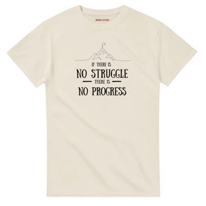May include: A cream-coloured t-shirt featuring the black text "If there is no struggle there is no progress". The design includes a mountain graphic with a flag. The brand name "MENOS STUDIO" is printed at the top.