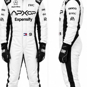 Puede incluir: Un traje de carreras blanco con paneles laterales negros, guantes OMP negros y zapatos de carreras OMP blancos. El traje presenta logotipos de APXGP, Expensify, IWC, Shark Ninja y GEICO. Se lleva un casco blanco con visera negra y marca APXGP.