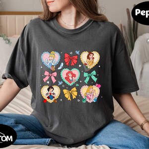 a woman sitting on a bed wearing a t - shirt