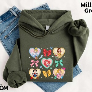 a green hoodie with a picture of princesses on it