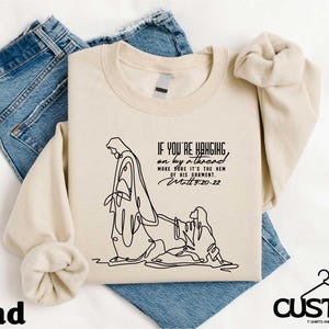 Vrouw met de kwestie raakt Jezus aan Shirt, T-shirt christelijk bijbelvers, vasthouden aan draad aan zoom van kledingstuk Trui, tekst vers bovenaan