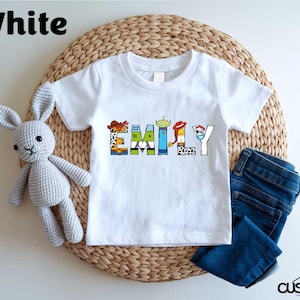a white t - shirt with the word family on it next to a stuffed animal