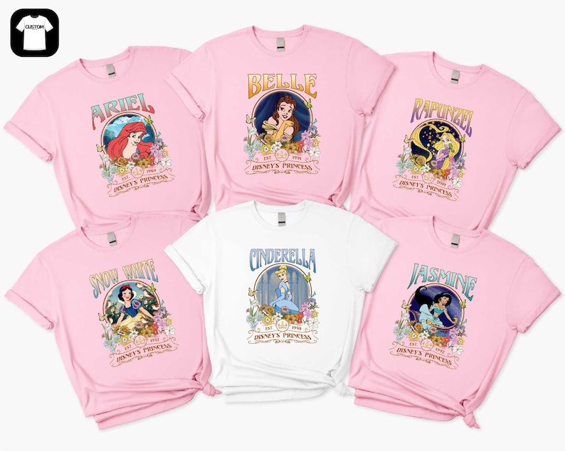 a collection of pink t-shirts featuring Disney princess characters, including Belle, Rapunzel, Snow White, Cinderella, and Jasmine.