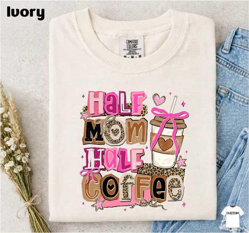 A white t-shirt with a colorful graphic design that says "Half Mom Half Coffee" along with a coffee cup and other decorative elements.