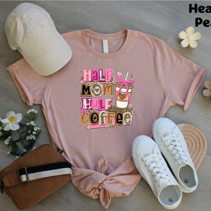 a pink t-shirt with a graphic design, a white baseball cap, a brown purse, a pair of white sneakers, and some flowers on a wooden surface.