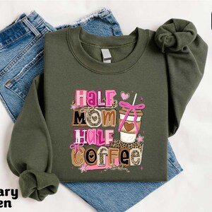A military green sweatshirt with a graphic design that says "Half Mom Half Coffee" and features a coffee cup and ribbon.
