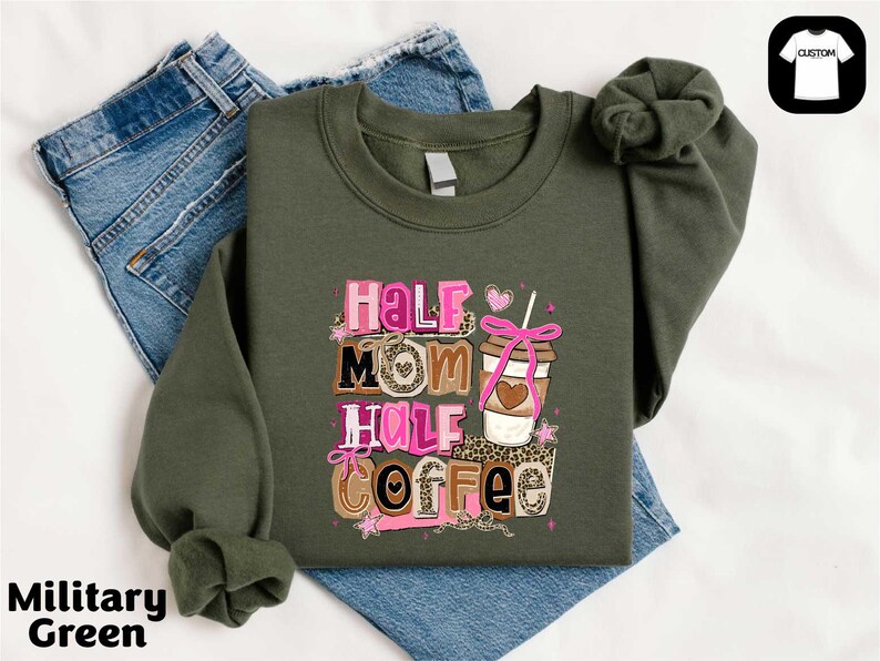 A military green sweatshirt with a graphic design that says "Half Mom Half Coffee" and features a coffee cup and ribbon.