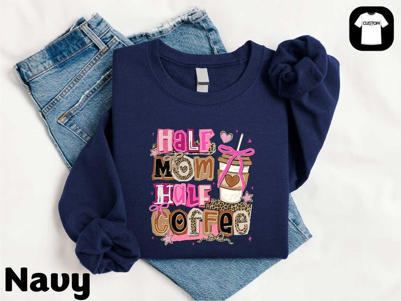 A navy blue sweatshirt with a colorful graphic design that says "Half Mom Half Coffee" printed on it, along with a coffee cup and other coffee-related items.