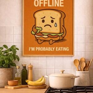 Può includere: Un poster incorniciato con la scritta "STREAM OFFLINE" e "I'M PROBABLY EATING" sopra e sotto un personaggio di un panino dei cartoni animati con una faccia triste. Il poster è in un ambiente cucina con utensili da cucina e cibo.