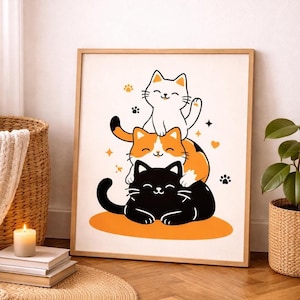 May include: A framed print featuring three cartoon cats stacked on top of each other. The bottom cat is black, the middle cat is orange and white, and the top cat is white. The print has a light wood frame and is displayed on a wall.
