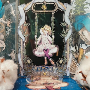 Può includere: Un'opera d'arte a strati e stravagante con una ragazza su un'altalena. L'altalena è sospesa a una cornice decorativa con una stella. La ragazza indossa un vestito bianco e calzamaglia viola. La base è una superficie blu con stelle.