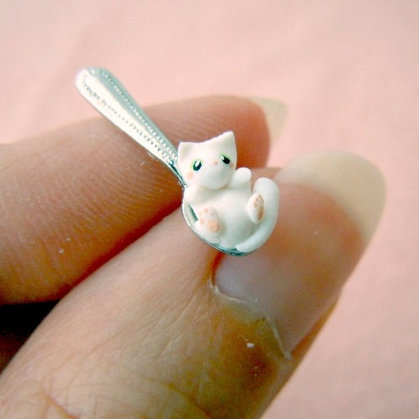 Tiny white kitten on a miniature dollhouse spoon