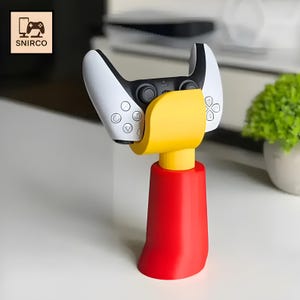 May include: A red, yellow, and black gaming controller stand. The stand holds a white and black controller. The stand has a red base, a yellow support, and the controller is black and white. The logo "SNIRCO" is in the top left corner.